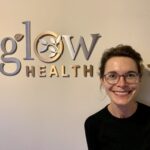 Headshot of acupuncturist Becca Bull in front of Glow sign, Seattle WA