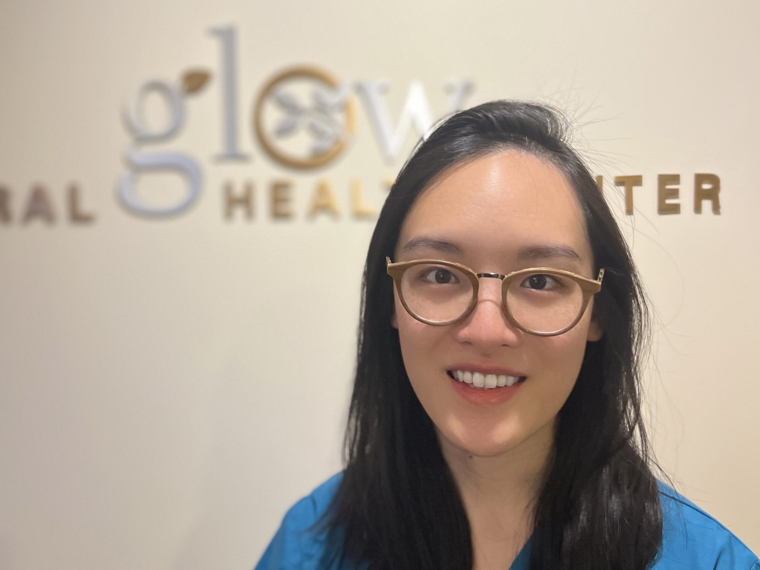 Kathy Lai headshot in front of metal Glow sign